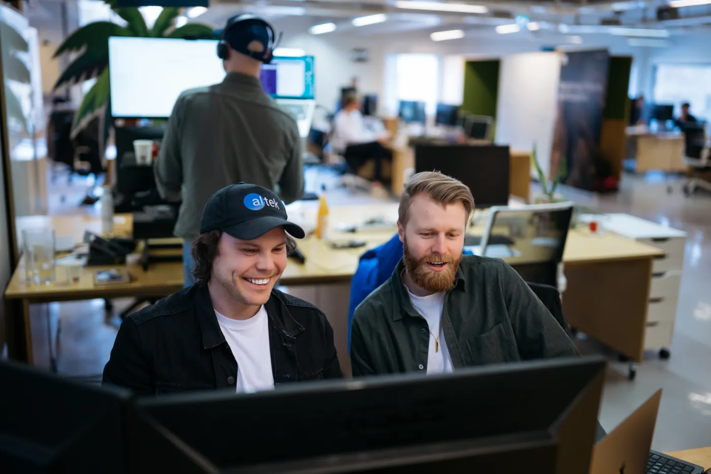 The two founders looking at a monitor in the Altek office, a teammate working behind them.