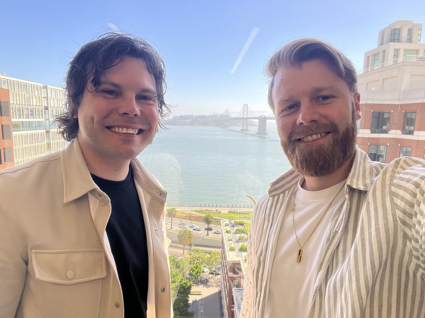 The two Altek founders taking a selfie high above the San Francisco waterfront, the Bay Bridge behind them.