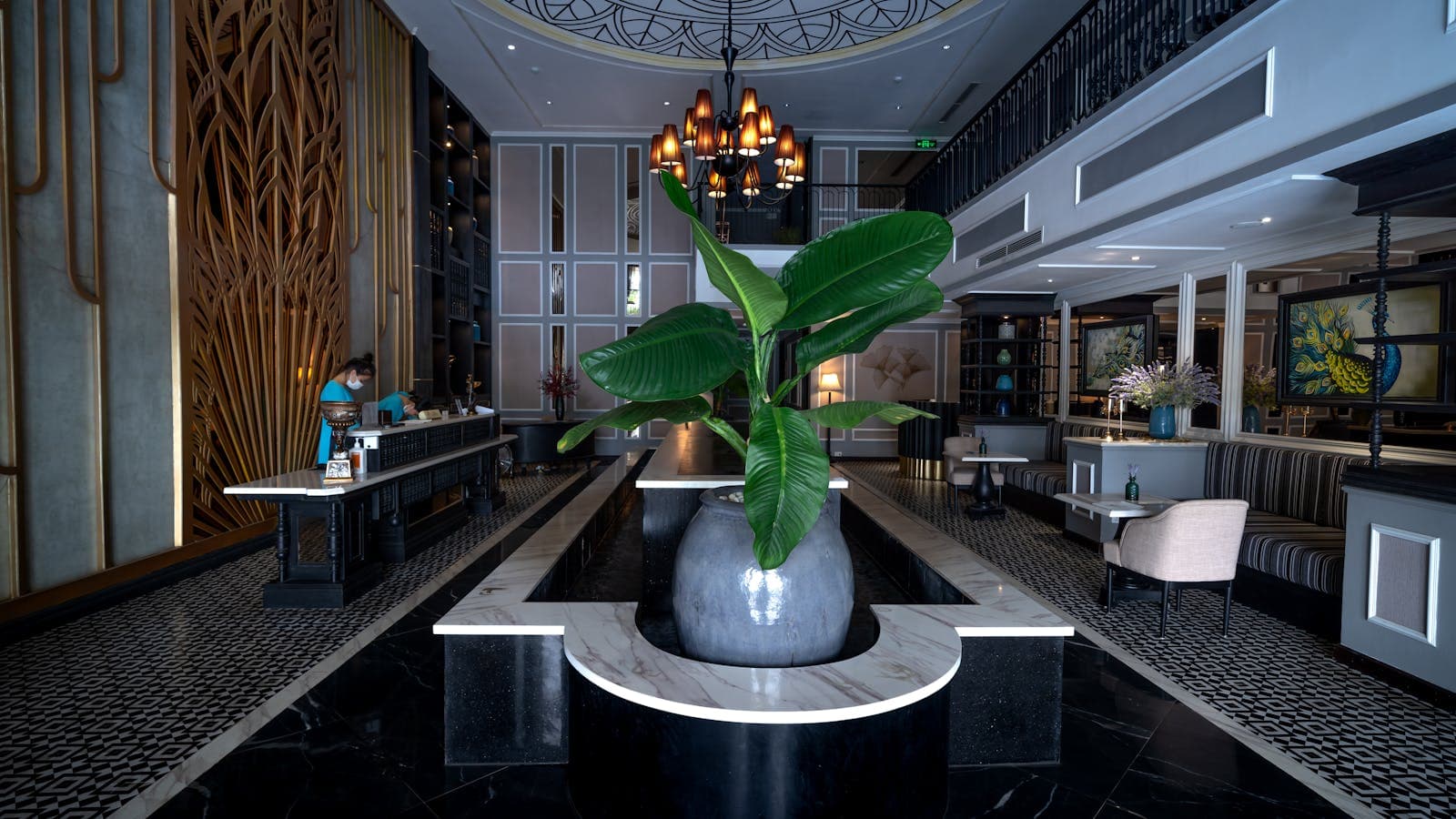 Sleek modern hotel lobby with a stylish chandelier and central plant arrangement — the kind of tech-forward property running Mews PMS.