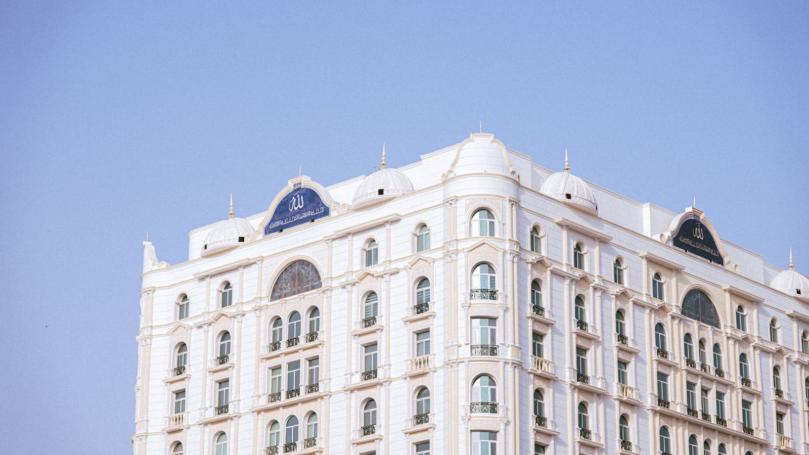 Luxurious white hotel facade with classic architecture under a clear blue sky — the destination guests are choosing when AI helps capture their direct inquiry.